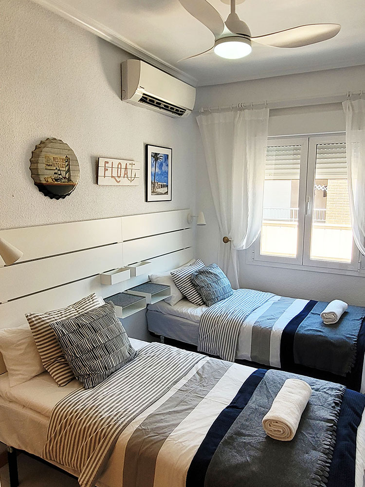 Bedroom with ceiling fan, aircondition, two single beds.
